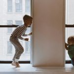Condo insurance - 2 children playing in the window sill of a condominium.